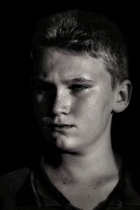 Close-up of boy against black background