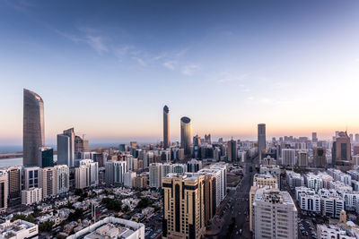 Modern buildings in city against sky during sunset