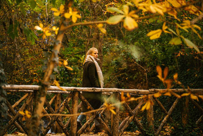 Man standing by tree in forest