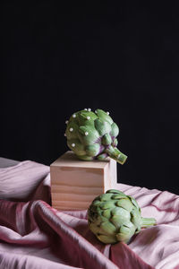 Close-up of hand holding vegetables against black background