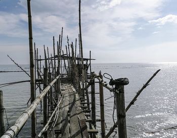 Metallic structure by sea against sky