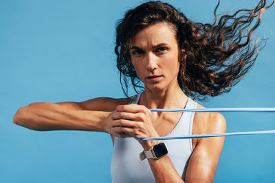 Portrait of woman exercising against blue background