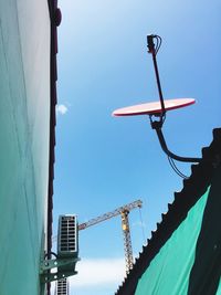 Low angle view of crane by building against clear sky