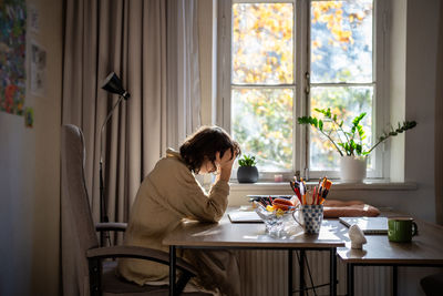 Rear view of woman sitting at home