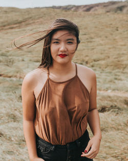 Portrait of beautiful young woman standing on field