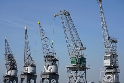 Low angle view of cranes against sky