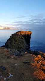 Rock formation by sea against sky during sunset