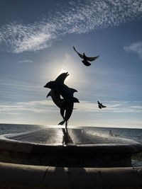 Seagulls flying over sea against sky