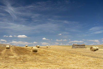 Hay bales on field against sky