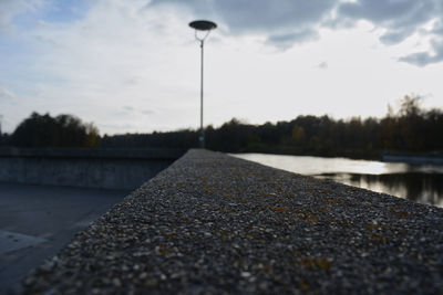 Surface level of street by lake against sky