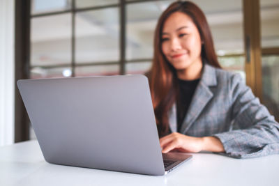 Closeup image of a young business woman working and typing on laptop computer keyboard 