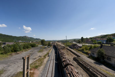 Railroad tracks along road and trees against sky