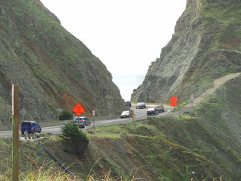 Vehicles on road by mountain against clear sky
