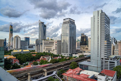 Modern buildings in city against cloudy sky