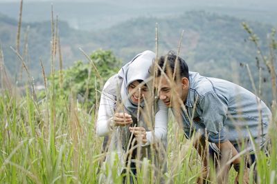 Couple looking at grass growing on field