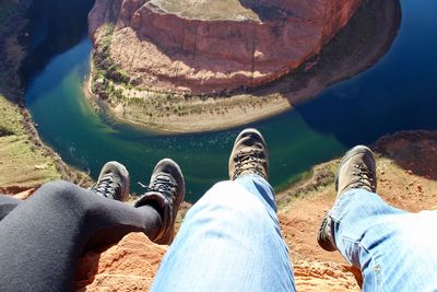 Low section of couple sitting at canyon