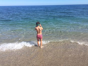 Rear view of young woman standing on beach