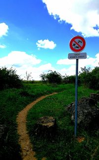 Road sign on field against sky