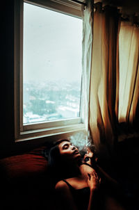 Side view of woman looking through window