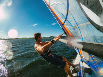 Wide-angle shot of adult man windsurfing on lake wallersee, austria