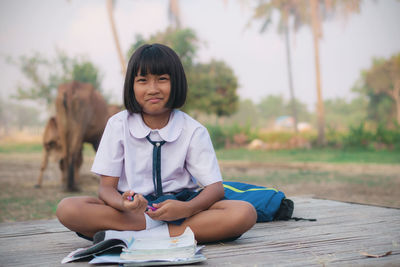 Portrait of smiling schoolgirl studying outdoors