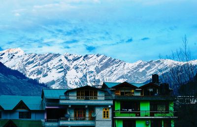 Houses by snowcapped mountains against sky