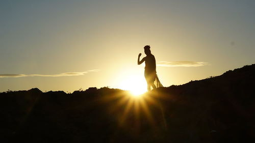 Silhouette woman standing against sky during sunset