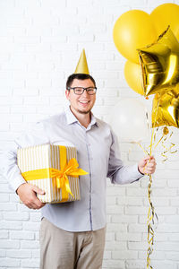 Midsection of man with balloons standing against wall