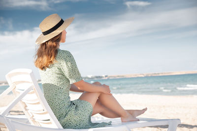 Rear view of woman sitting on beach