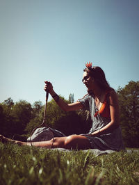 Midsection of man sitting on field against clear sky