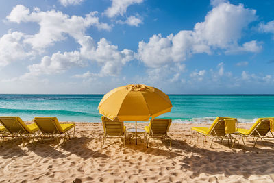 Deck chairs on beach against sky