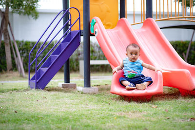 Boy sitting on slide at playground