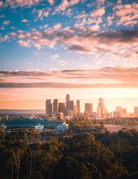 Modern buildings in city against sky during sunset