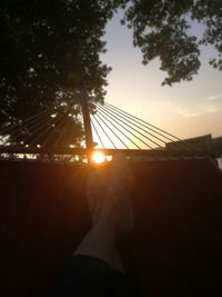 Silhouette person on hammock against sky during sunset
