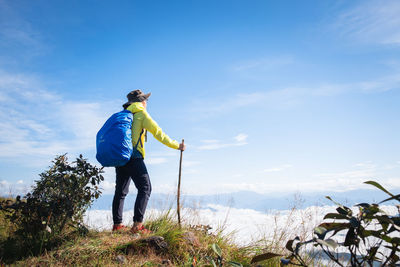 Rear view of woman standing on mountain against sky