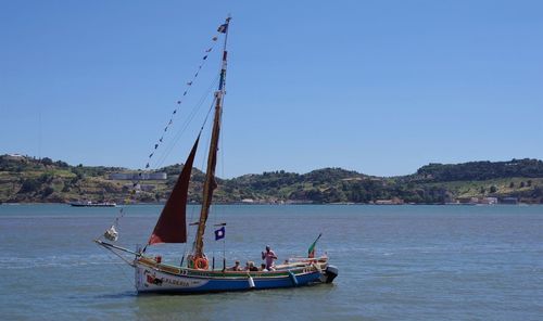 Sailboat sailing on sea against clear blue sky