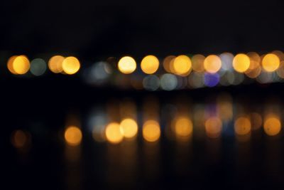 Defocused image of illuminated lights in sea at night