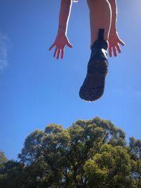 Low section of person jumping against trees