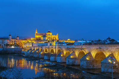 Arch bridge over river against blue sky