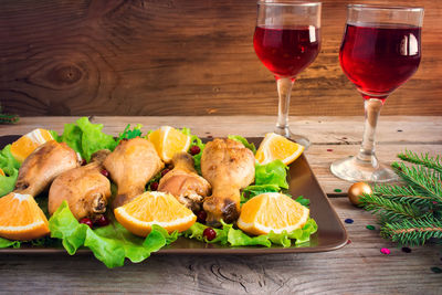 Baked chicken legs on a plate with greens, oranges and cranberri