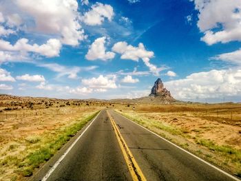 Road amidst field against sky