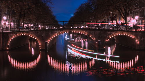 Illuminated bridge over river at night