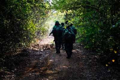 Out focus and blur rear view of thai soldiers holding gun walking on trail in forest