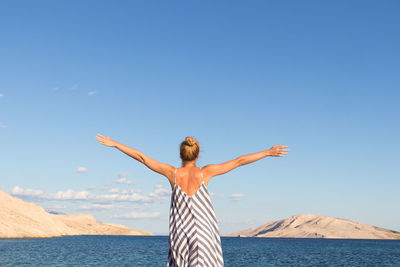 Woman standing by sea against sky