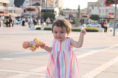 Portrait of smiling girl walking on footpath in city