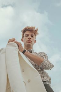 Low angle view of young man looking away against sky