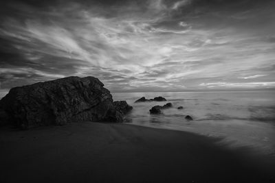 Scenic view of rocks on beach against sky