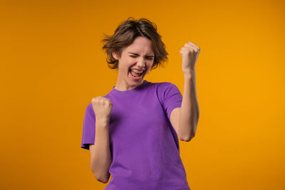 Young woman standing against yellow background