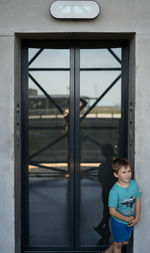 Cute boy standing against door