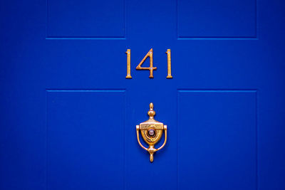 House number 141 on a blue wooden front door